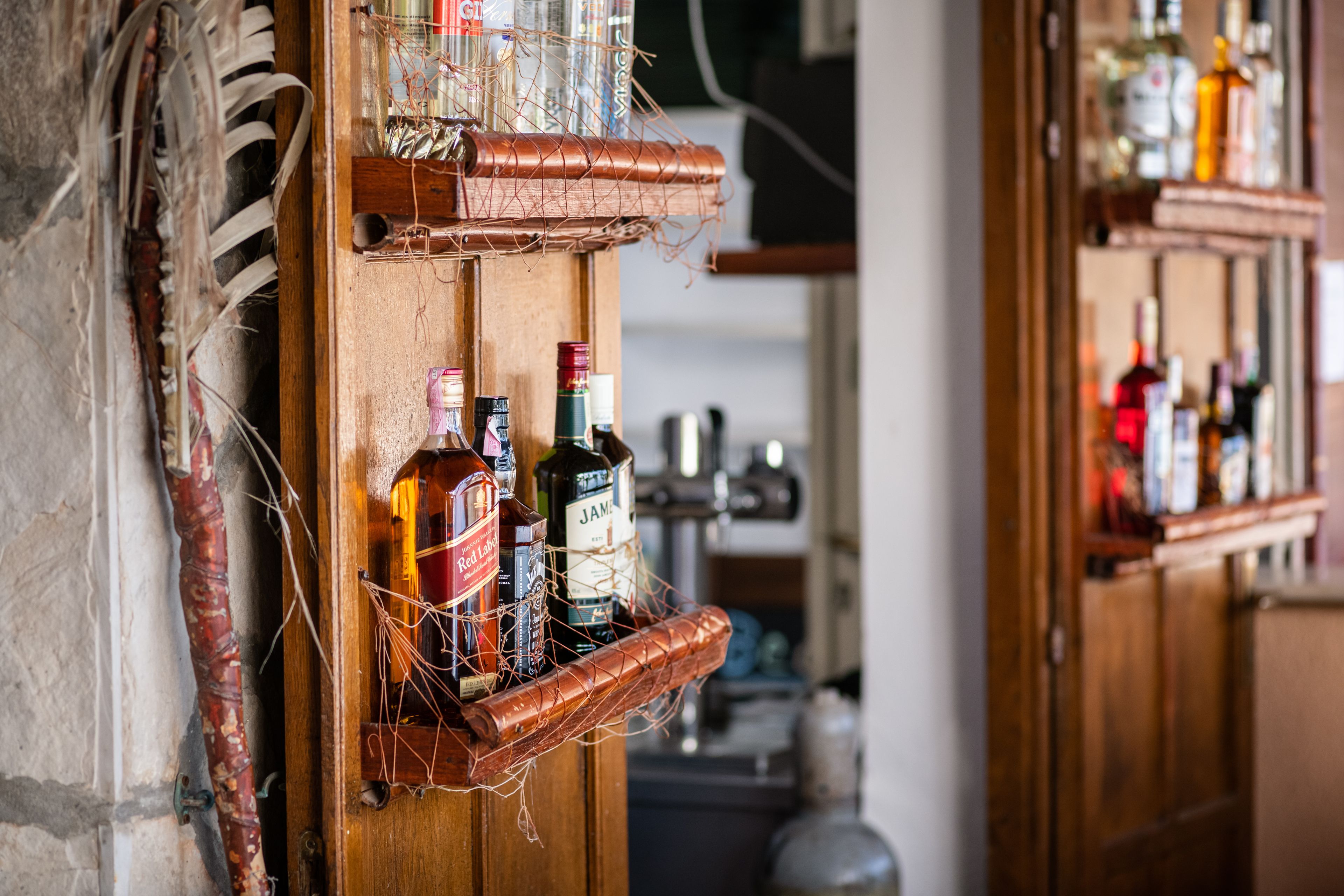 A wooden shelf with bottles and glasses, likely in a bar or restaurant setting.