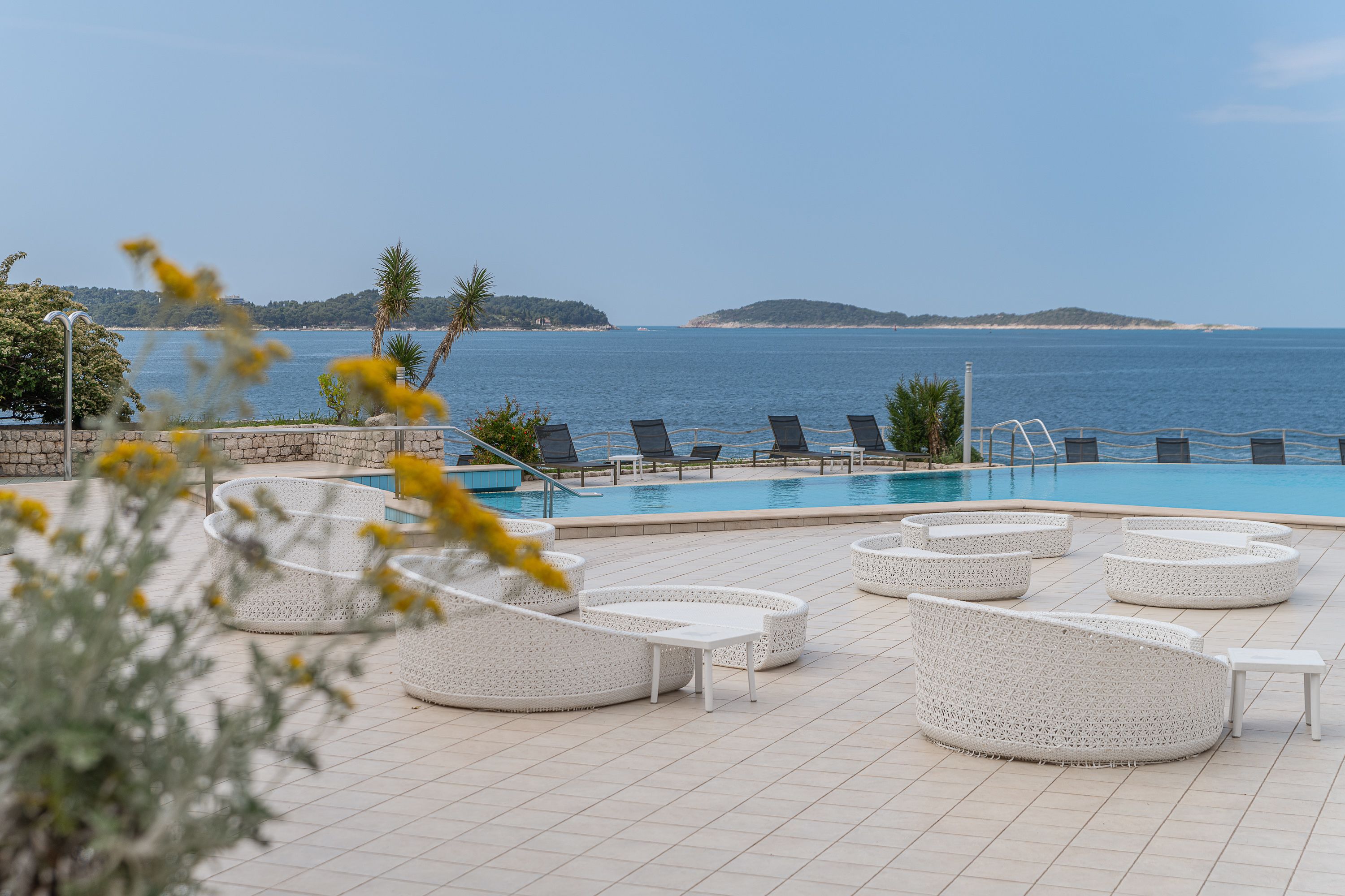 Un espace aménagé au bord de la piscine, avec des chaises longues et une vue sur la mer.