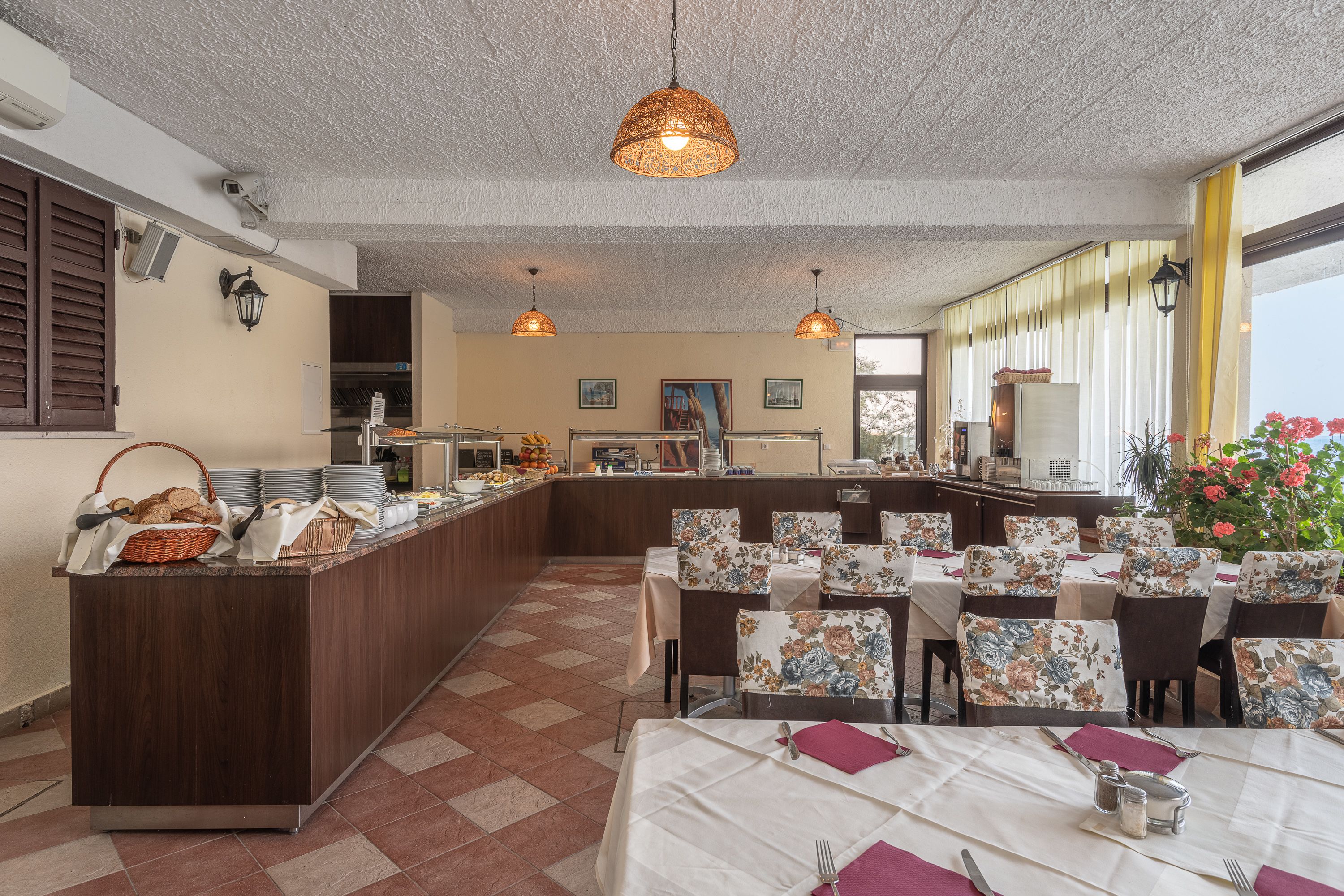 A dining area with tables set for service, a buffet counter, and a view of the outdoors.