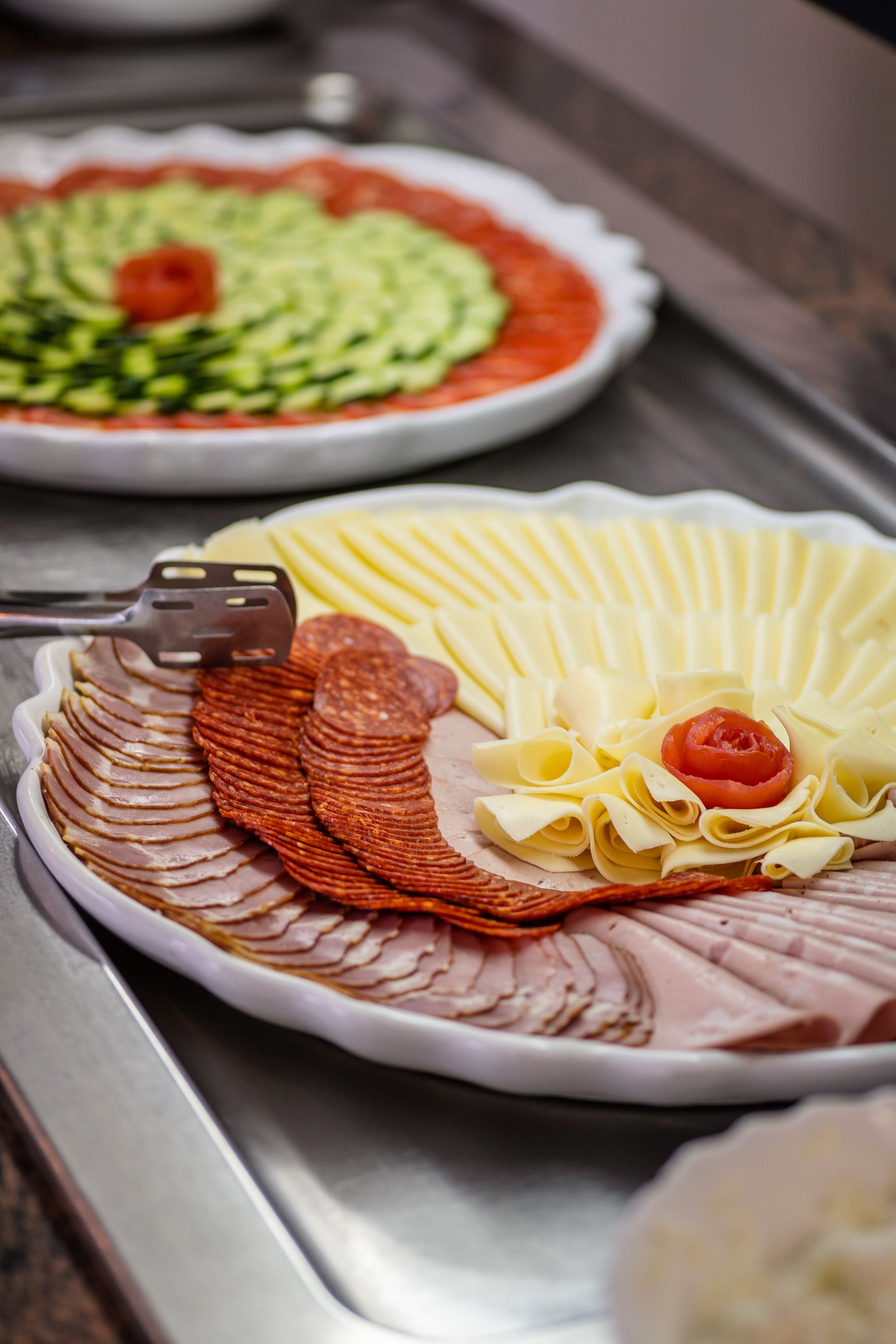 A buffet with sliced meats, cheese, and vegetables.