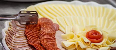 A buffet with sliced meats, cheese, and vegetables.