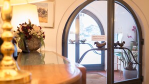Una habitación con un amplio ventanal de arco, un jarrón con flores y un cartel que pide cerrar la puerta.