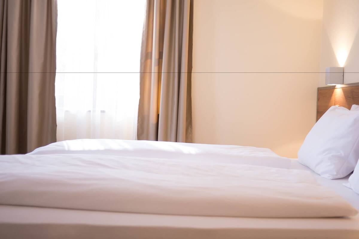 A neatly made bed with white linens in a hotel room.