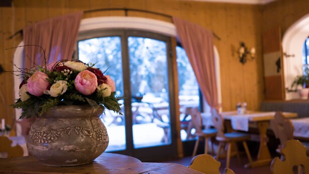 Un interior rústico de madera con un ventanal grande y una mesa con un arreglo floral.