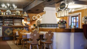 Un restaurante con barra, sillas de madera y suelo de baldosas.