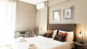 Une chambre d’hôtel avec un lit bien fait, un bureau, une chaise et deux œuvres d’art accrochées au mur.