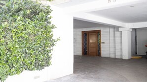 Un couloir avec un mur vert, une porte en bois et un sol carrelé.