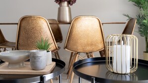 Un espace repas moderne avec une table ronde, un bol, une tasse et une bougie dans une cage en métal.