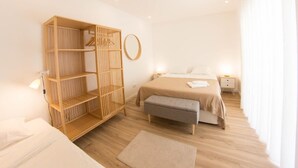 Une chambre moderne avec une armoire en bois, un lit avec un banc gris et un miroir rond accroché au mur.