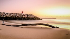 Une plage avec une digue rocheuse et un phare.