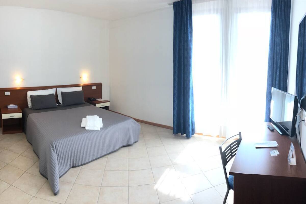 Habitación de hotel con cama, mesitas de noche, escritorio y televisión.