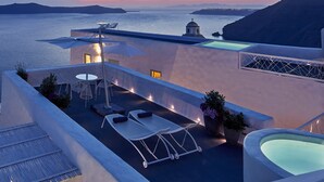 Une terrasse sur le toit avec des chaises longues, une petite table et un espace piscine.