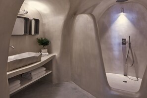 A modern bathroom with a built-in sink, a shower, and a shelf with towels. - Limestone (Santorini)