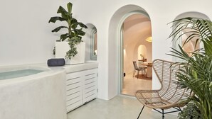 Un intérieur moderne avec une baignoire, des meubles blancs et un coin repas comprenant des chaises et une table.