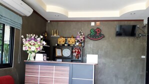 A reception desk with a clock, framed photos, and a sign that reads "SP Resort". - SP Resort (Lahan Sai)
