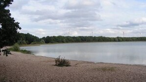 A calm lake with a sandy shore and trees in the background. - Ferienwohnung Kerstin (Siggelkow)