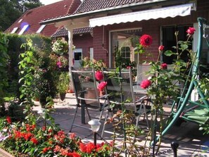 A house with a porch, a garden with flowers, and outdoor furniture.