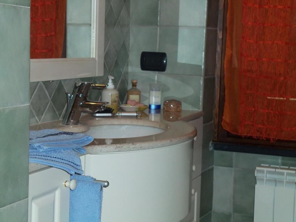 A bathroom with a sink, mirror, and toiletries.