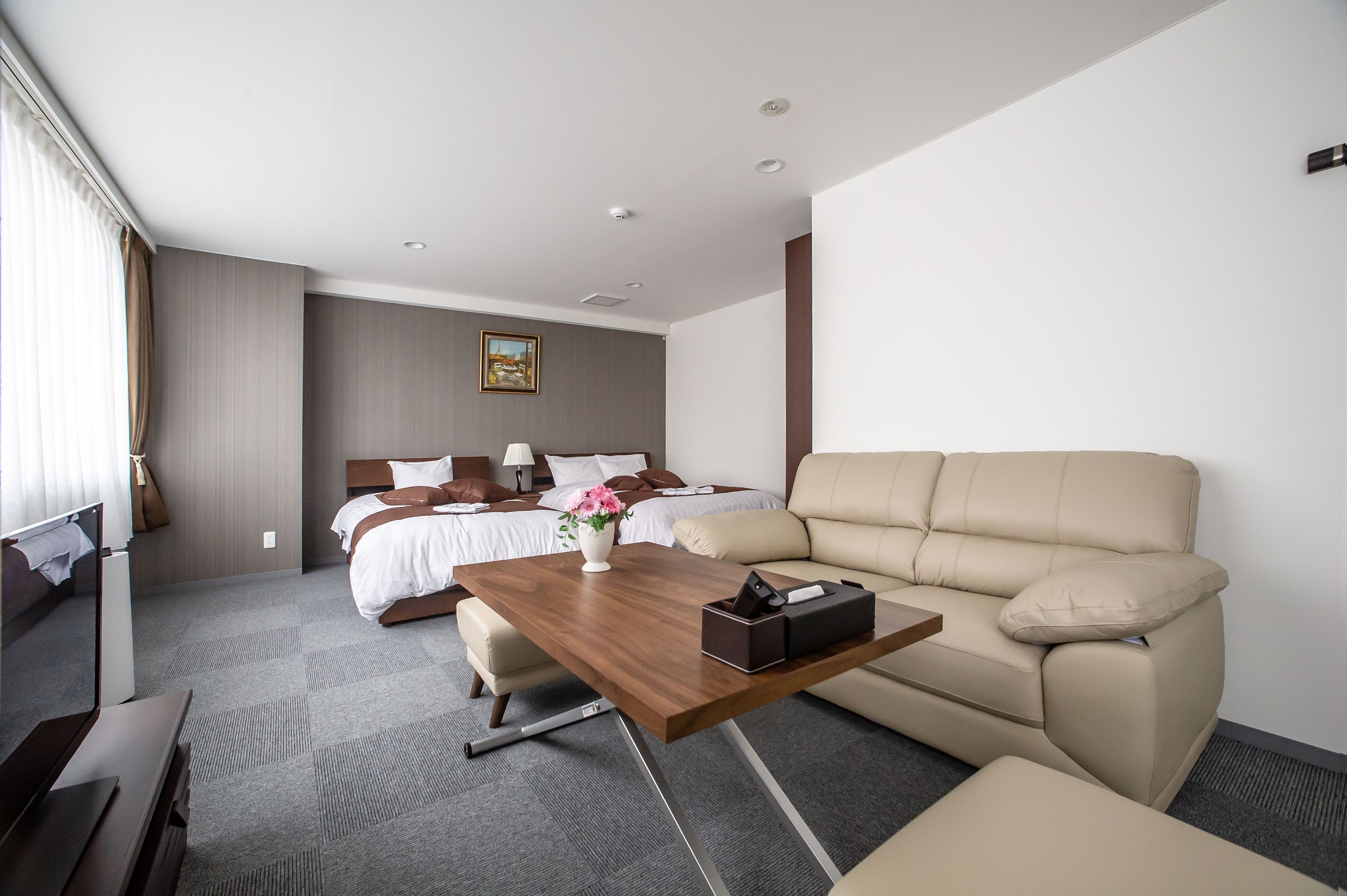 Ein Hotelzimmer mit Bett, Sofa, Couchtisch aus Holz und Schreibtisch.