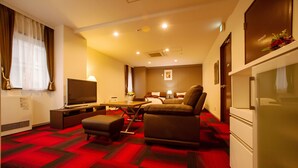 A hotel room with a bed, a sofa, a TV, a desk, and a refrigerator. - Condominium Stella Site (Hakodate)