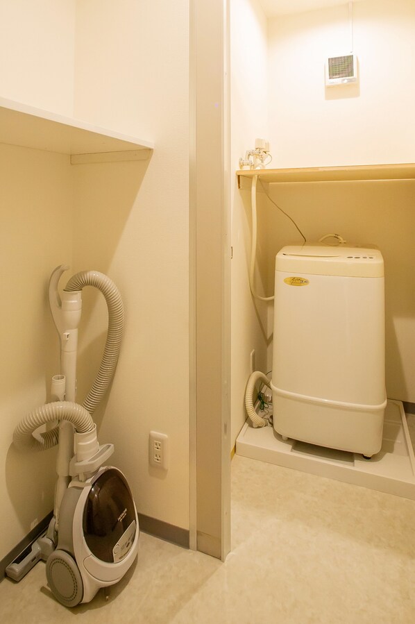 A compact bathroom with a white toilet, a white sink, and a white water heater.