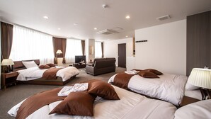 A hotel room with three beds, a sofa, a TV, and a desk with a lamp. - Condominium Stella Site (Hakodate)