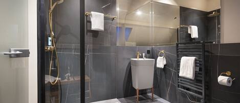 A modern bathroom with a glass-enclosed shower, a vanity with a sink and mirror, and a towel rack.