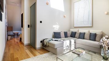 A modern living room with a sectional sofa, a glass coffee table, and a large abstract painting on the wall.