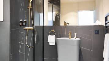 A modern bathroom with a glass-enclosed shower, a vanity with a sink, and a mirror.