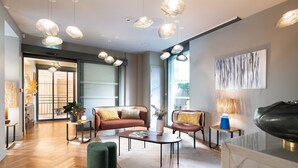A modern living room with a sofa, chairs, a coffee table, and pendant lights. - Hebe Hotel (Annecy)