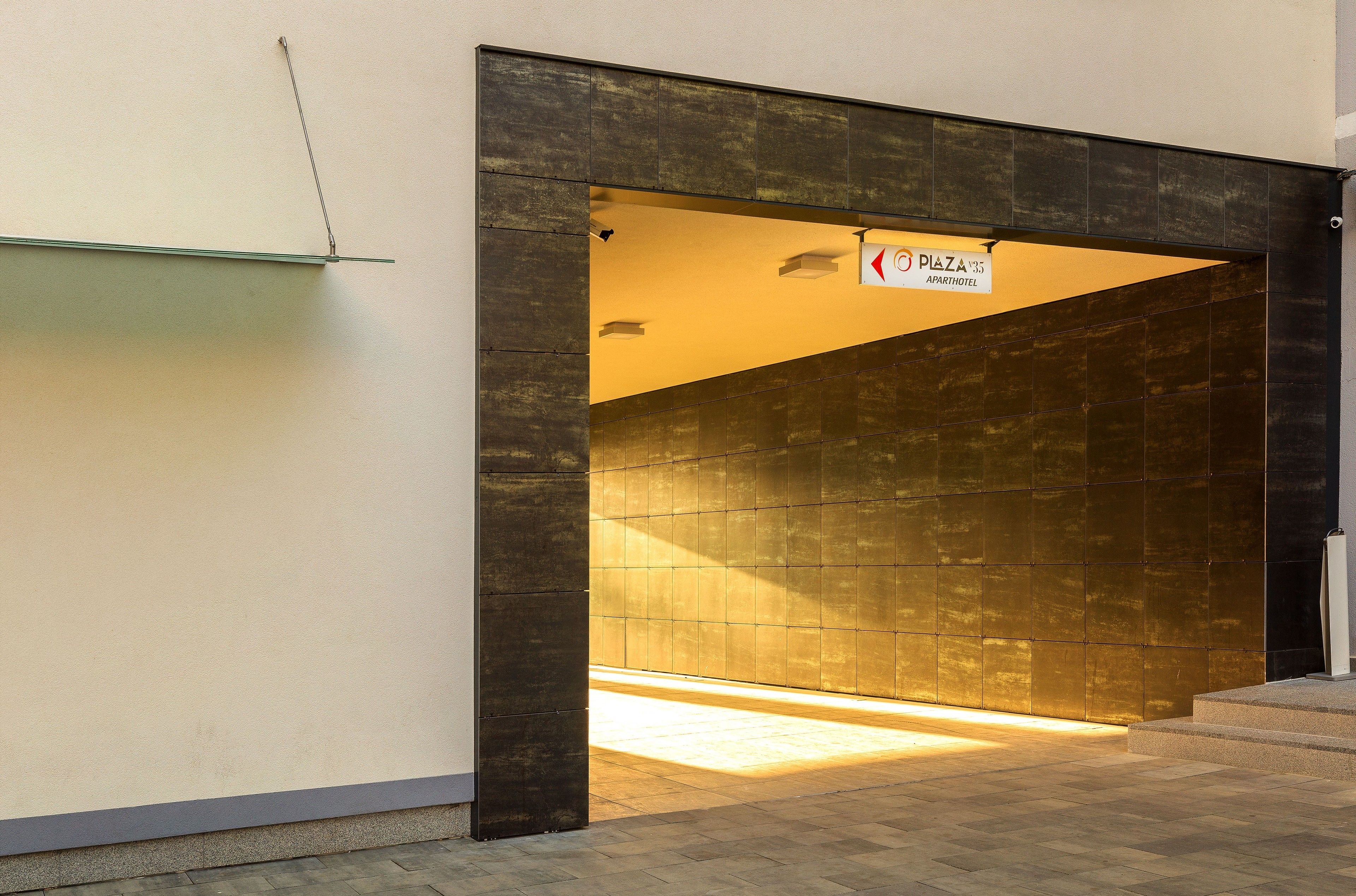 A modern building entrance with a sign for 'Plaza 375 Apart Hotel'.