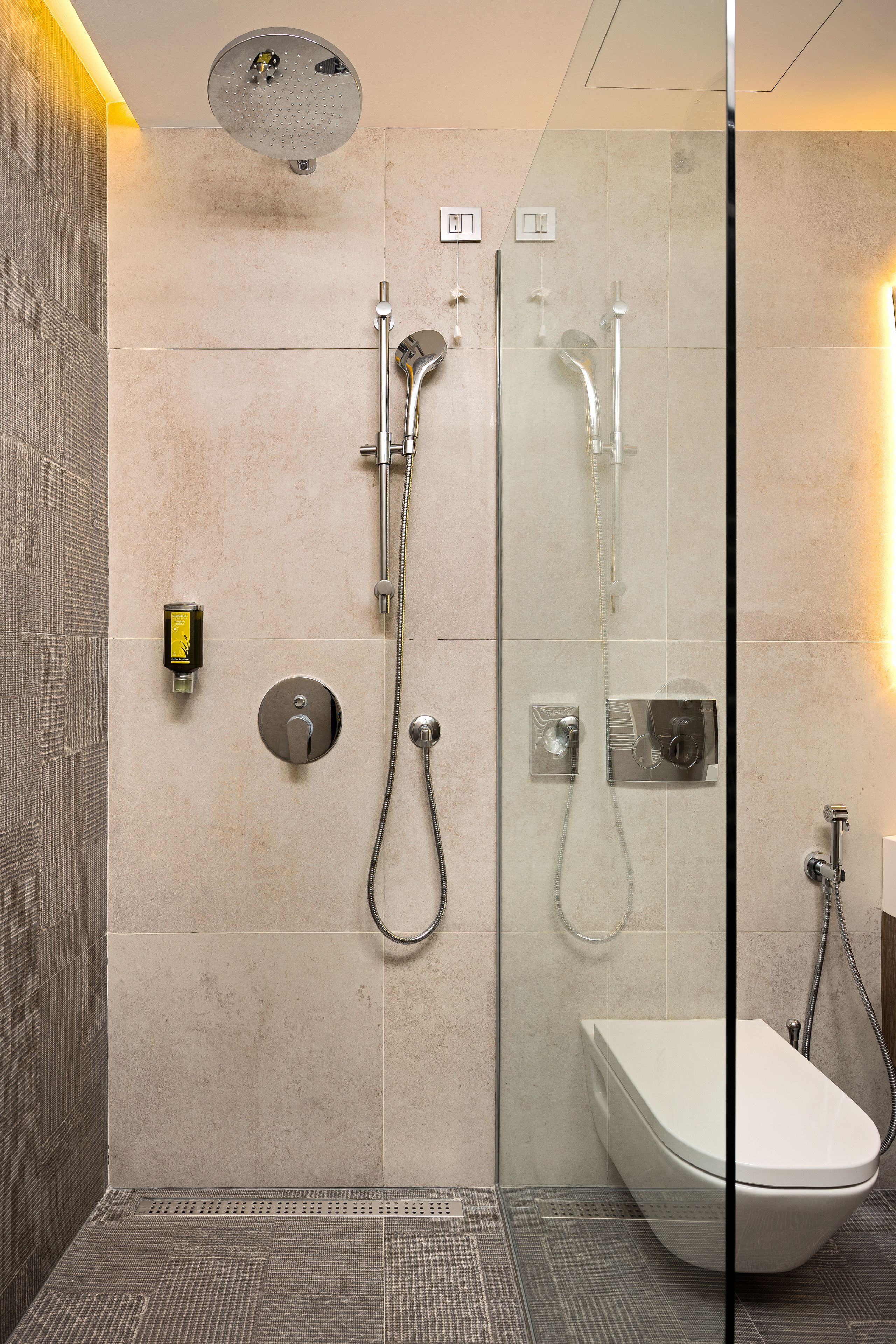 Un baño moderno con ducha de vidrio, inodoro independiente y lavamanos empotrado.