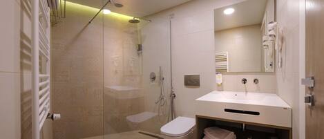 Un baño moderno con cabina de ducha de vidrio, lavabo blanco y retrete.