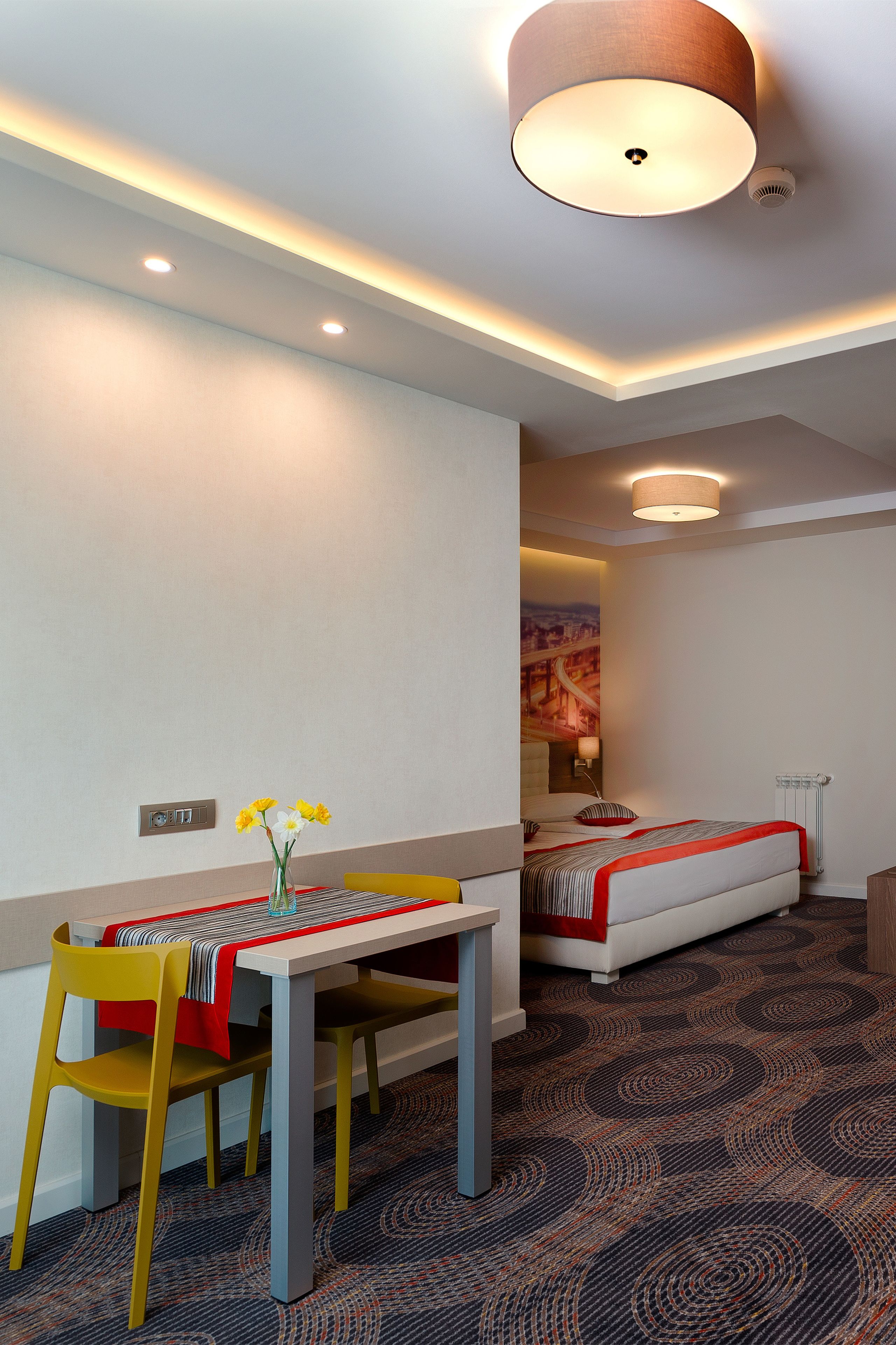 A hotel room with a dining table, chairs, a bed, and a carpeted floor.
