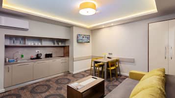 Una habitación de hotel moderna con kitchenette, zona de comedor y sofá.