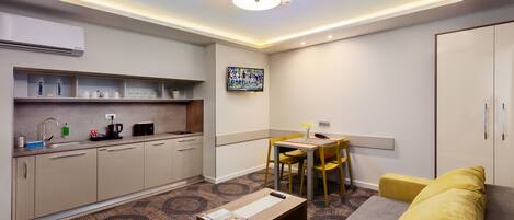Una habitación de hotel moderna con kitchenette, zona de comedor y sofá.