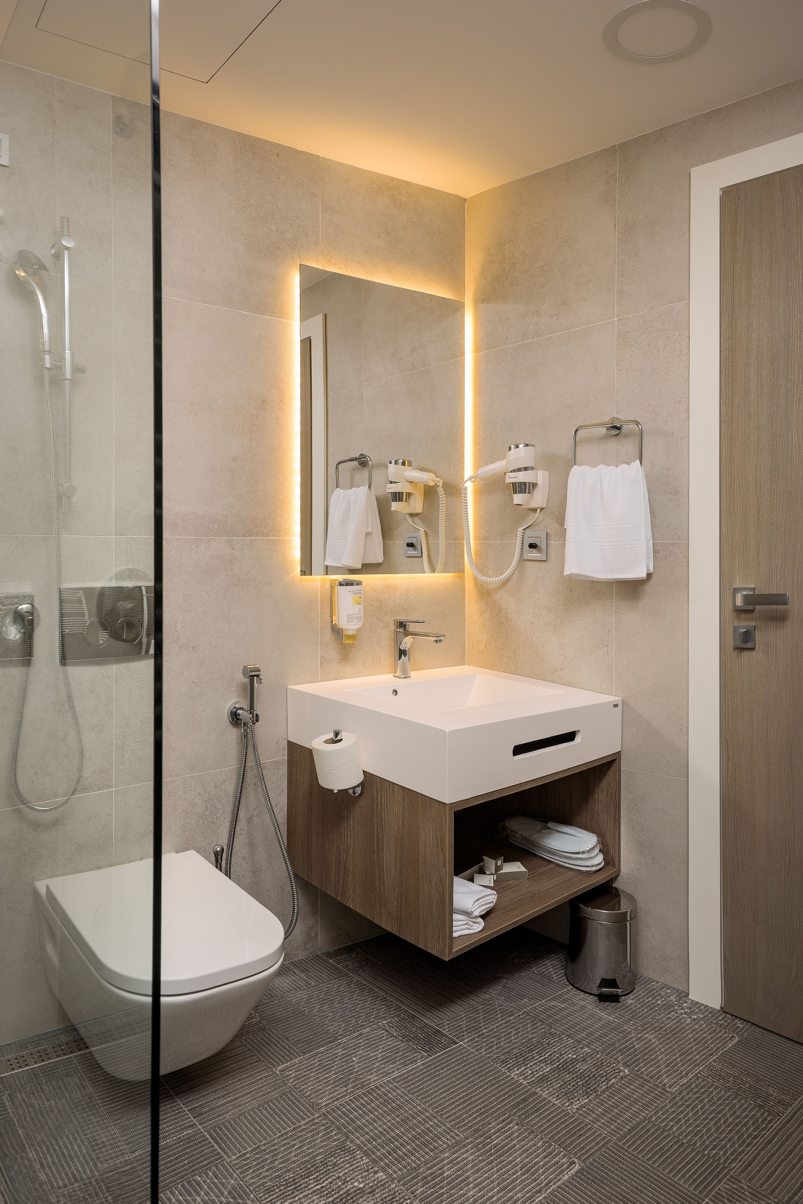 Une salle de bain moderne avec une douche à parois de verre, un lavabo blanc et un meuble-lavabo en bois.