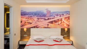 A hotel room with a large bed, two bedside tables, a headboard, a wall-mounted light fixture, and a cityscape mural on the wall.