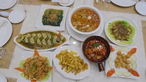 Une table dressée avec divers plats, notamment des fruits de mer, une soupe et des légumes.
