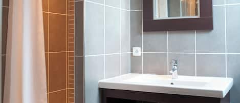 Ein modernes Badezimmer mit Dusche, Waschbecken und Spiegel.