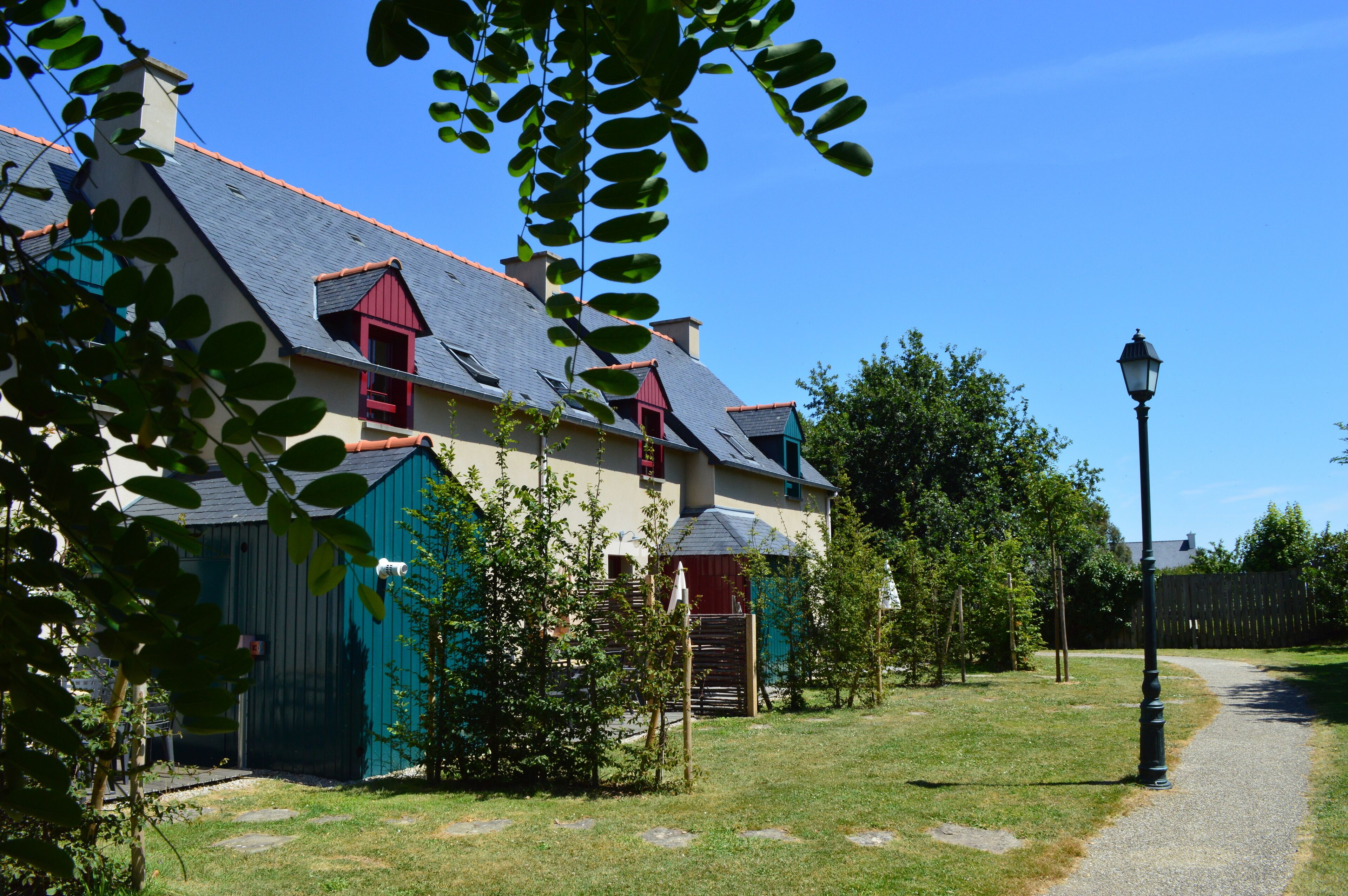 Een huis met een schuin dak, een rode schoorsteen en een pad dat ernaar leidt.