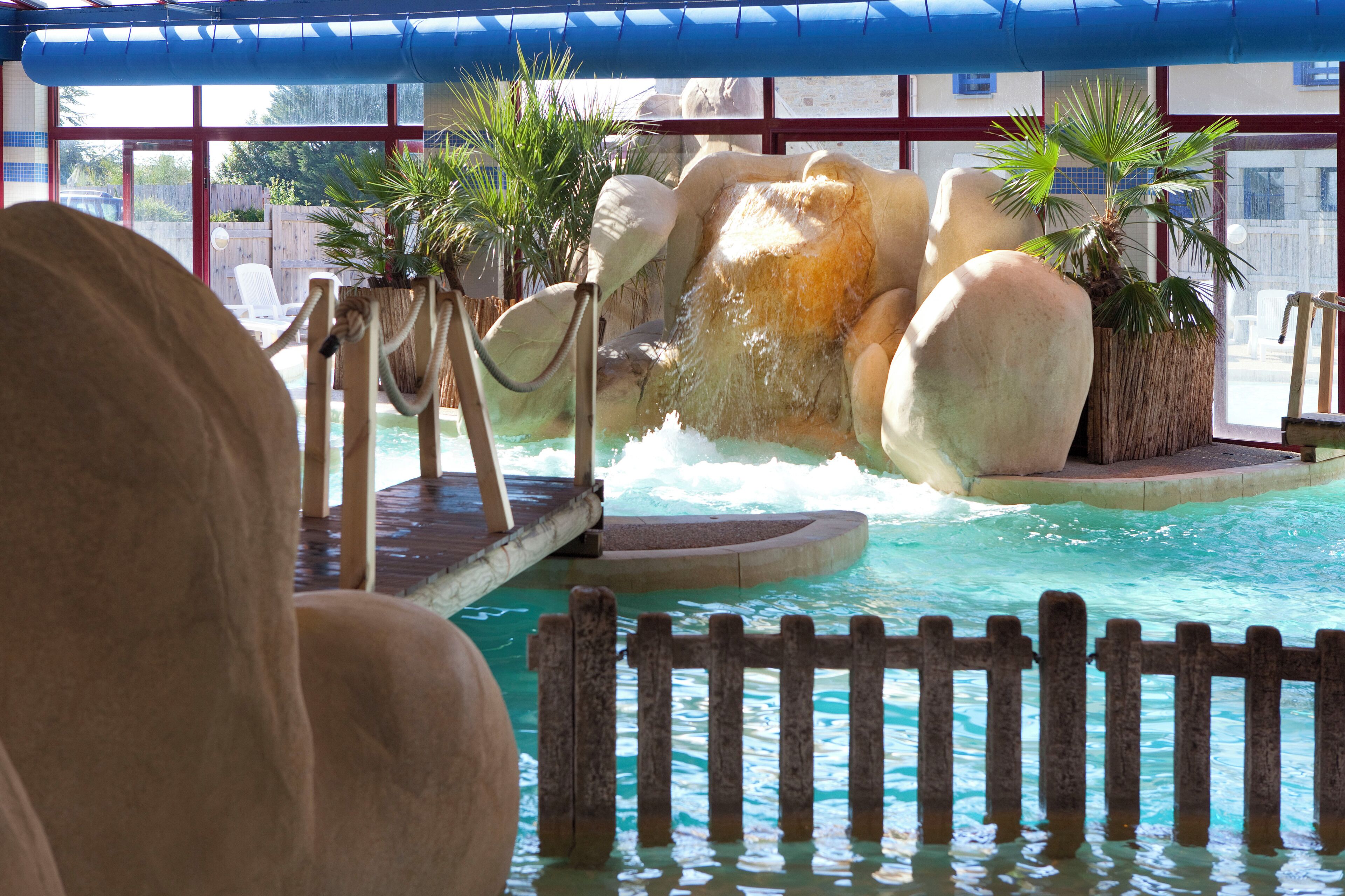 Una piscina con cascada, rocas y plantas en macetas.
