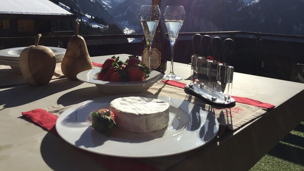 A table set with food and drinks, overlooking a mountainous landscape. - Stunning ski & walking chalet with best views in Wengen (Lauterbrunnen)