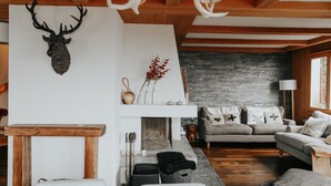 A cozy living room with a fireplace, a mounted deer head, and a grey sofa with patterned cushions. - Stunning ski & walking chalet with best views in Wengen (Lauterbrunnen)