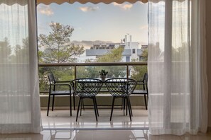 Ein Balkon mit zwei Stühlen und einem Tisch, mit Blick auf eine Wohngegend mit Gebäuden und Bäumen.
