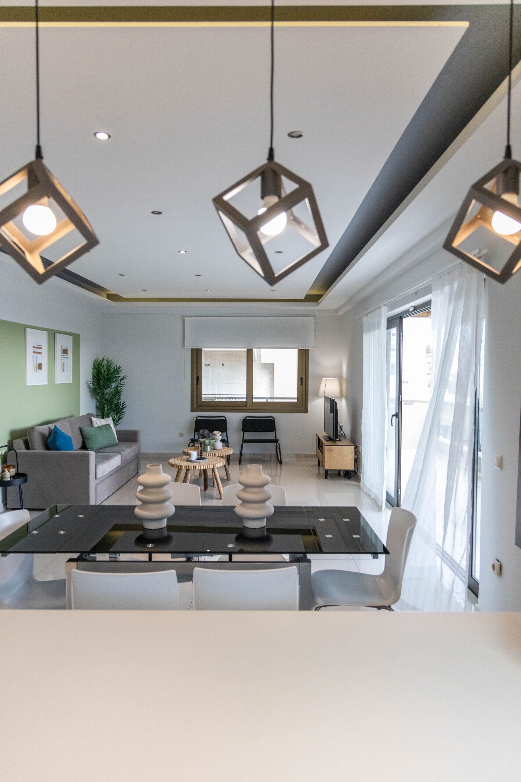Un salon moderne comprenant un canapé, une table à manger, des chaises et des lampes suspendues.