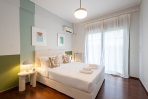 A neatly arranged bedroom with a large bed, bedside lamps, and a window with curtains.