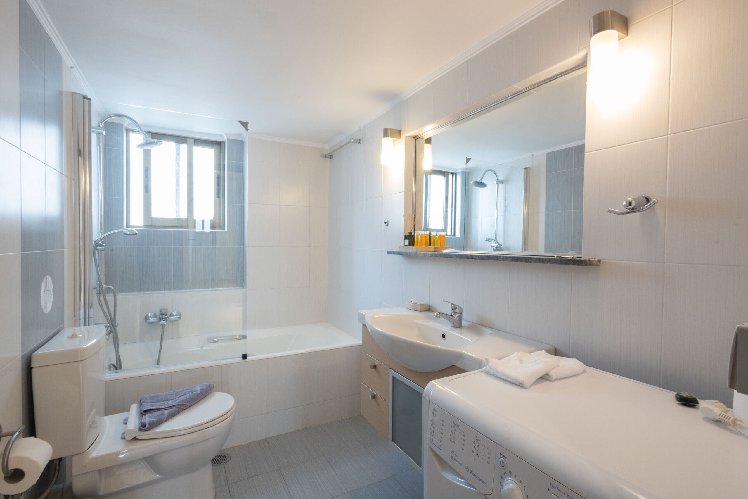 A modern bathroom with a bathtub, toilet, sink, and a mirror.