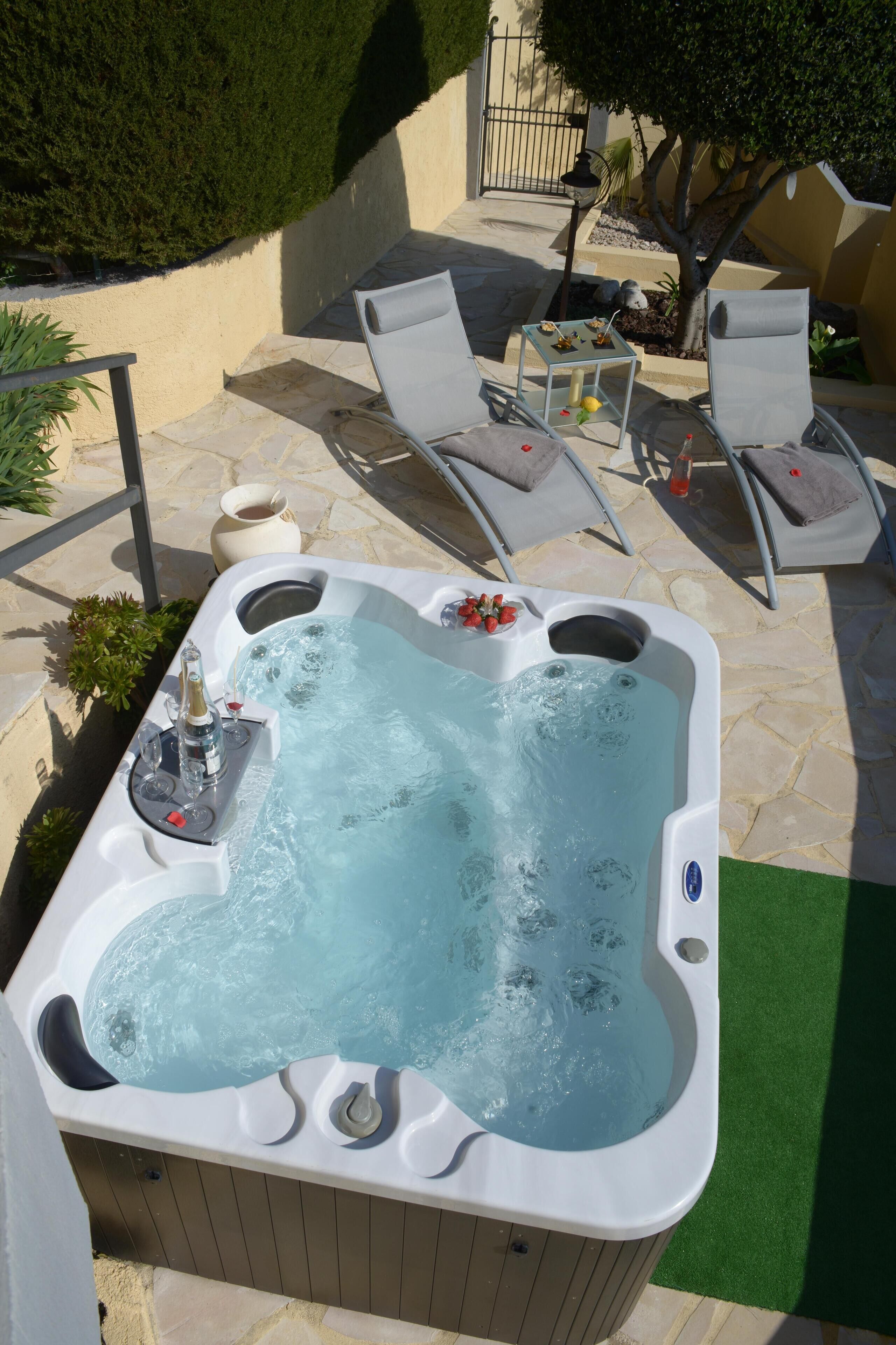 A hot tub with jets, surrounded by stone tiles and outdoor furniture.