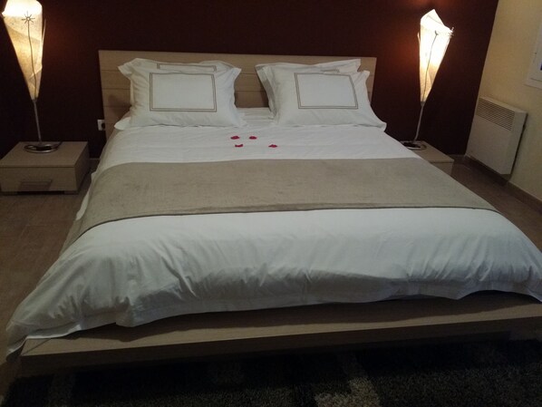 A neatly made bed with white linens and a beige throw blanket, flanked by two bedside lamps.